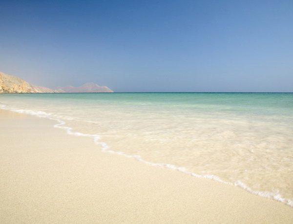 View of the sandy beach with the clear waves at Six Senses Zighy Bay in Oman