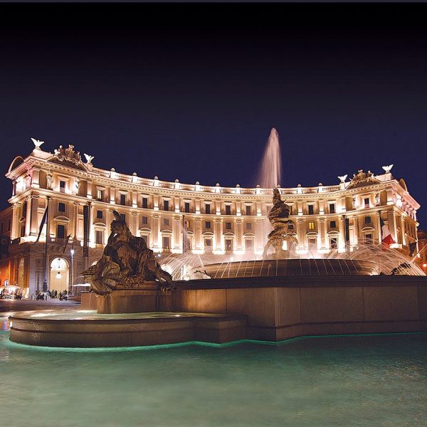 View of the exterior and fountain at night of the Boscolo Exedra Roma in Italy